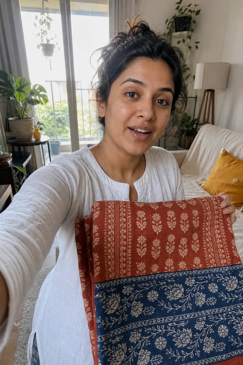 Woman in a sunlit living room holding a block-printed table runner up to the camera